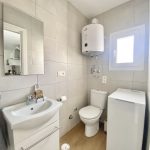 Baño completo con lavabo, inodoro, calentador de agua y lavadora.