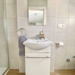 Lavabo de baño con espejo y accesorios decorativos.