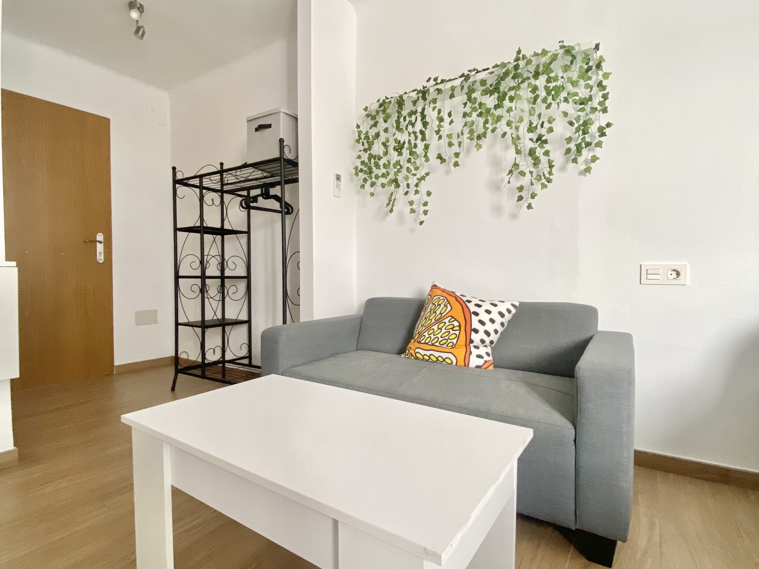Sala de estar con sofá gris, mesa de centro y detalles decorativos.