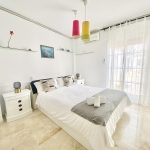 Habitación moderna con cama doble, almohadas decorativas y luz natural, ideal para descanso y relajación.
