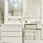 Mueble de baño blanco con lavabo y cestas de almacenamiento en un ambiente moderno y luminoso, ideal para organización y estilo.