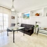 Sala de estar con sofá gris, mesa de vidrio y decoración minimalista, ideal para un ambiente acogedor y moderno.