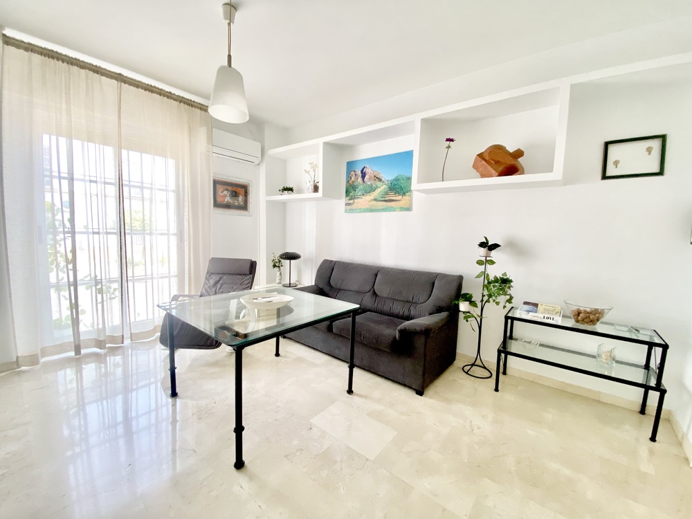 Sala de estar con sofá gris, mesa de vidrio y decoración minimalista, ideal para un ambiente acogedor y moderno.