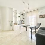 Sala de estar moderna con sofá gris, mesa de cristal y estanterías blancas, ideal para decoración y diseño de interiores.